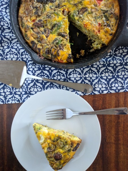 One slice of dairy free frittata on plate, the rest in cast iron pan.