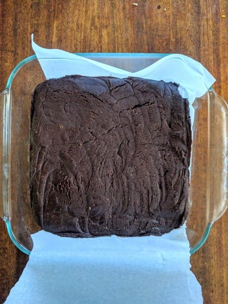 Press the brownie batter down in the baking dish. Parchment paper underneath makes it easy to pull out.