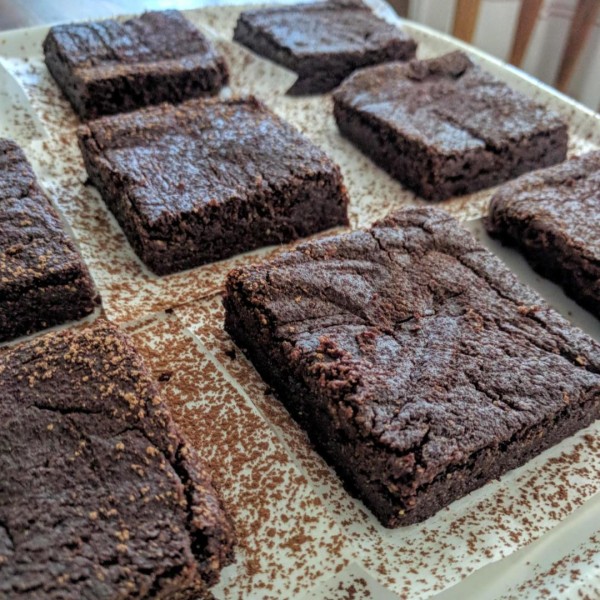 brownies on white plate, dusted with cocoa powder.