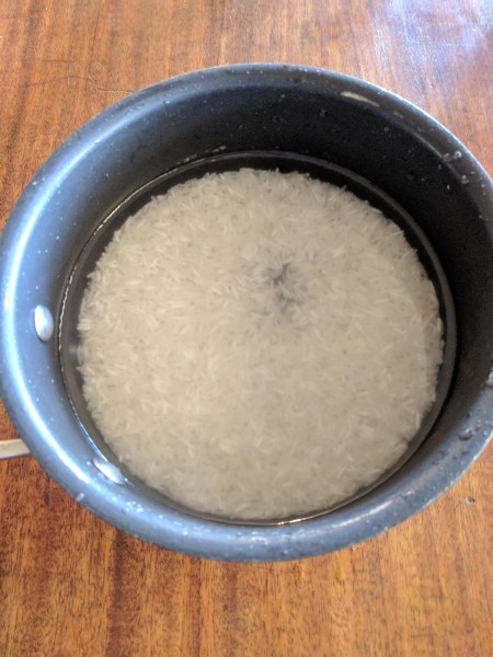 rice in pot after rinsing a few times. The water is much clearer than in the first rinse.