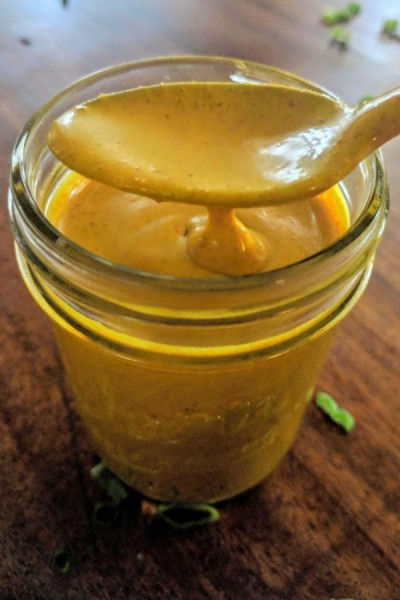Curry sauce dripping off spoon into jar.