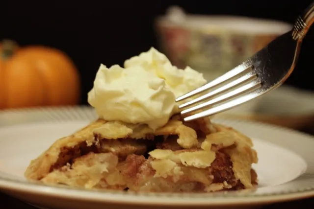 a slice of gluten-free apple pie topped with a dollop of ice cream with a fork