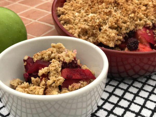 baked Blackberry and apple crumble in a white bowl; the rest of the crumbles in a red bowl 