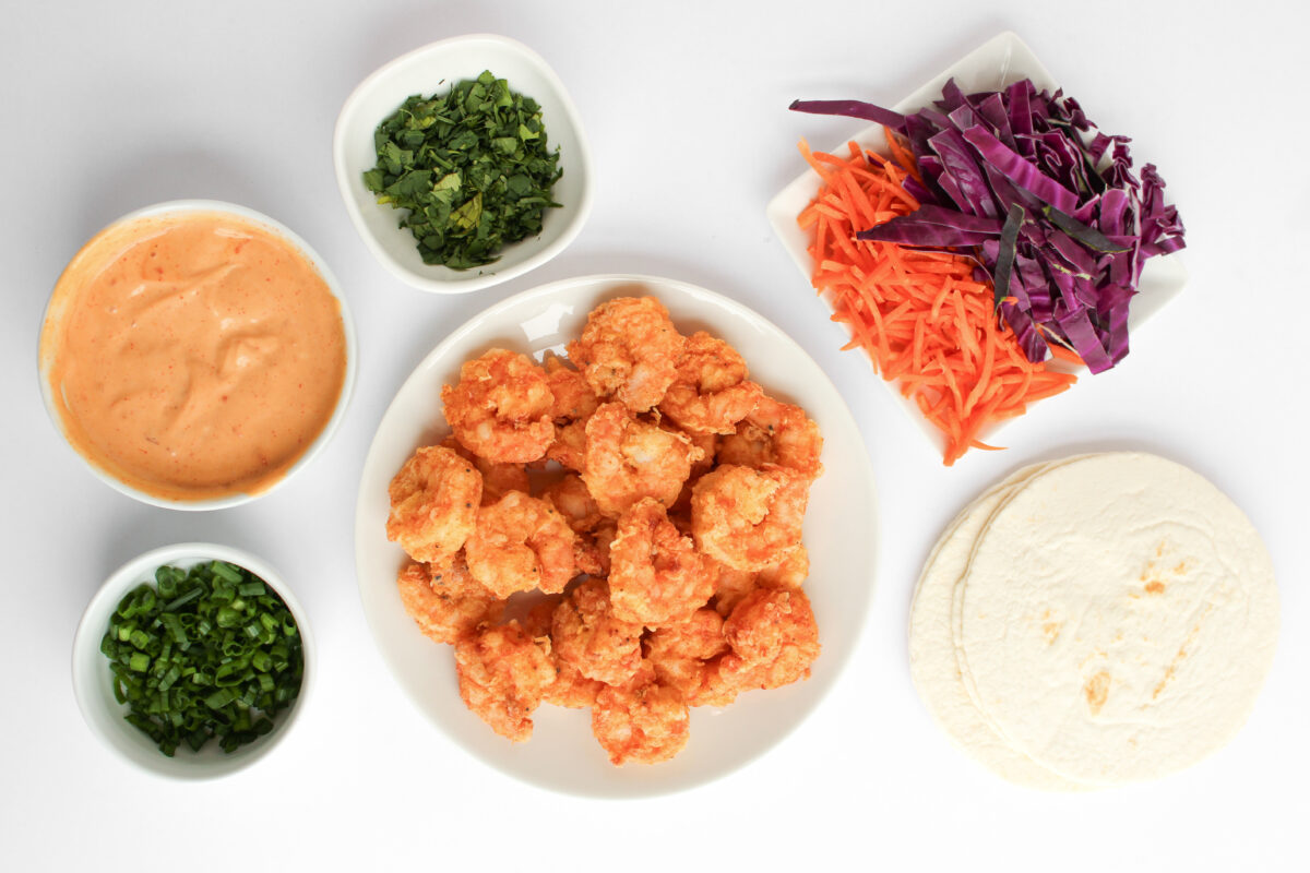 Bang bang shrimp taco ingredients in individual bowls on white background