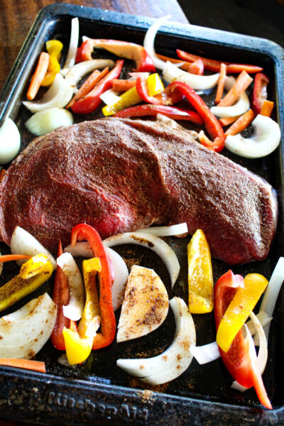 steak (with seasoning) and veggies on sheet pan ready to bake