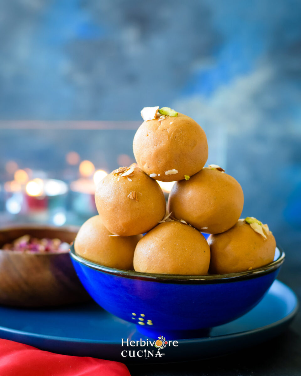 stacked besan ladoo balles with nuts on a blue dessert bowl