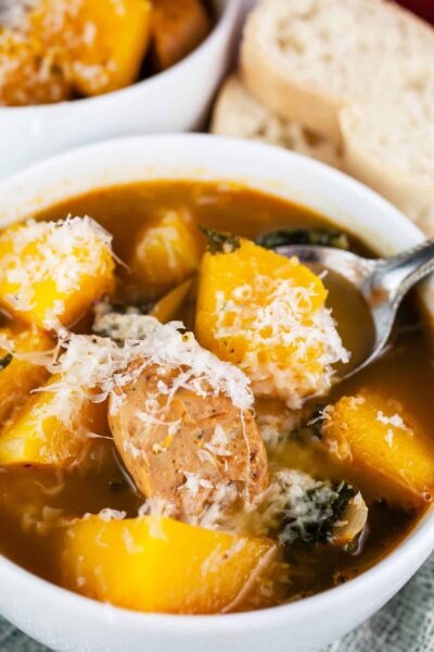 Chunky Butternut Squash Sausage Soup in a white bowl with a spoon