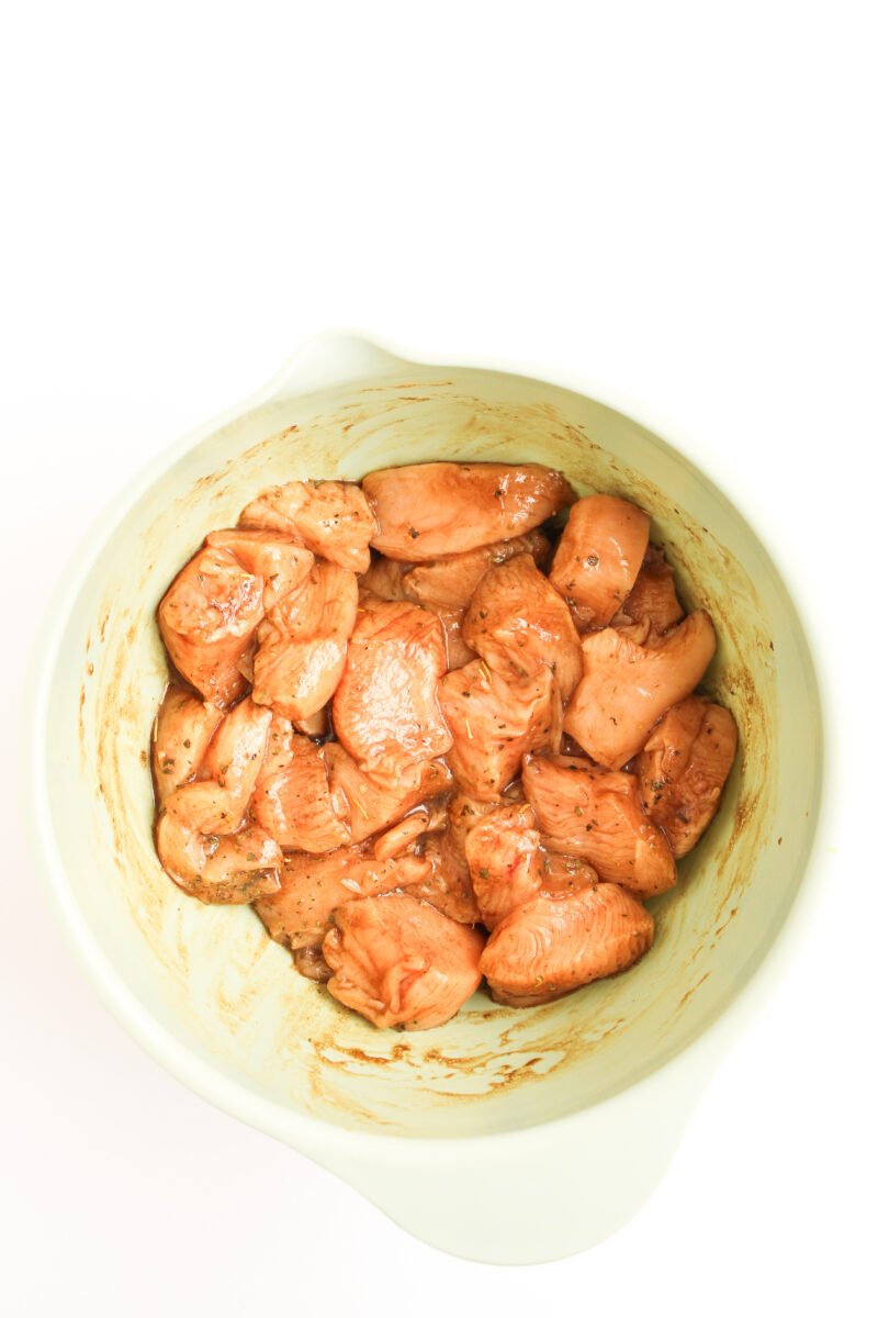 Marinating chicken in green mixing bowl.