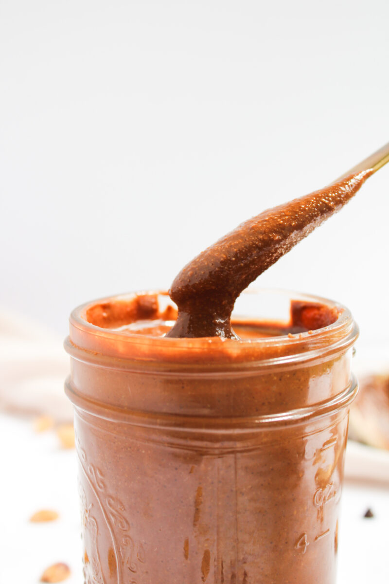 A butter knife dipping into a jar filled with chocolate peanut butter