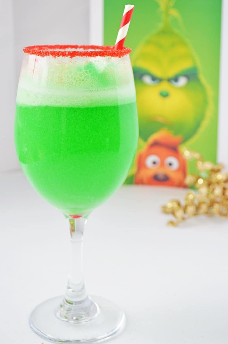 nonalcoholic Christmas grinch punch in a cocktail glass rimmed with red sanding sugar