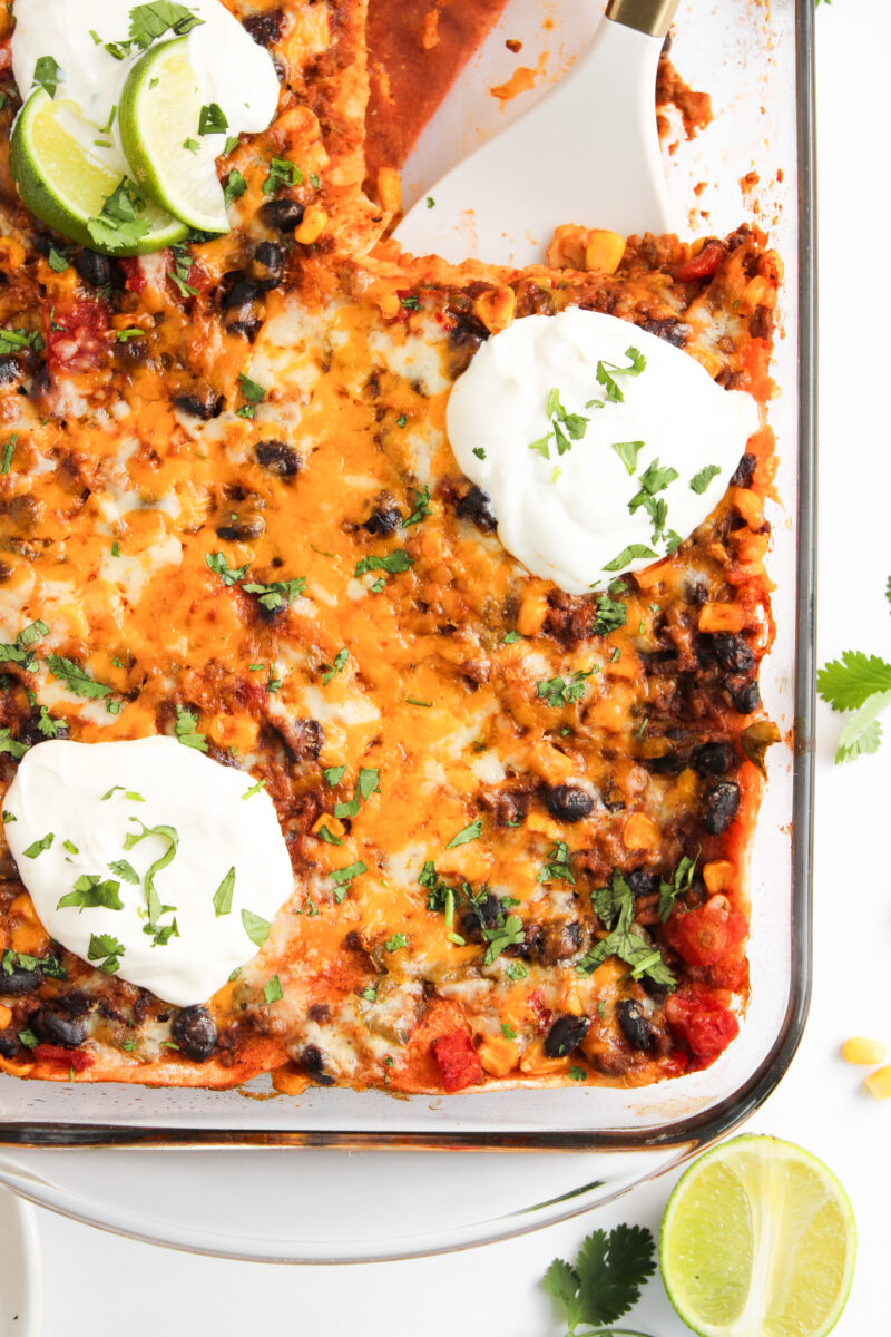 Corner of casserole dish with half of a lime and cilantro in the background.