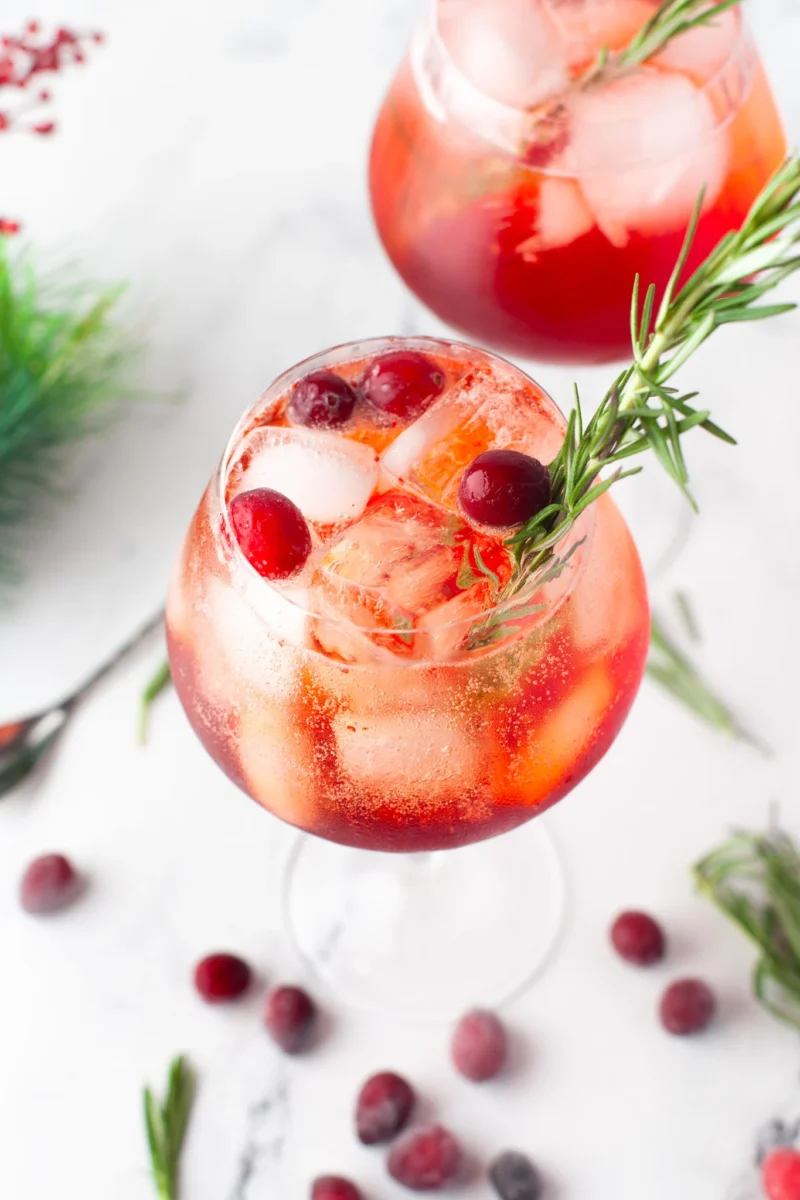 cranberry aerosol spritz in a cocktail glass with ice, cranberries, and sprig of rosemary