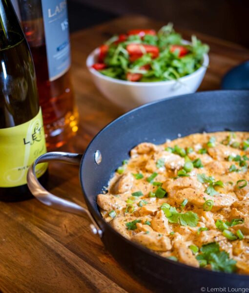 cooked chicken slices with creamy sauce topped with herbs in a pot with handles