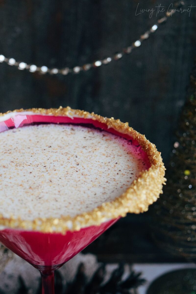 close image of eggnog martini rimmed with sugar in a pink-red martini glass