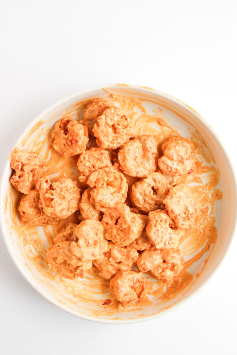 Fried shrimp tossed in bang bang sauce in a large white bowl
