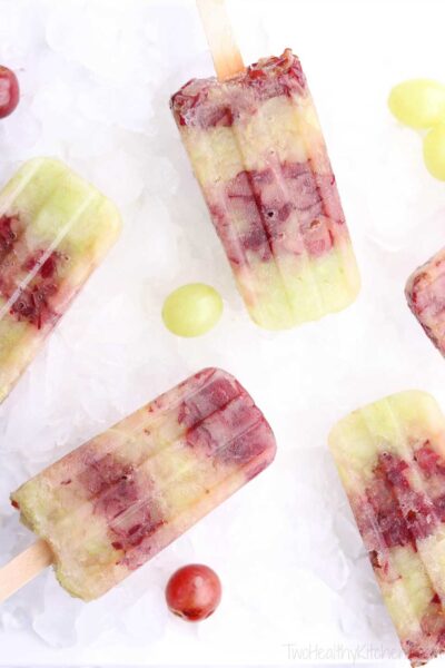 frozen grapes popsicles on top of ice cubes with pieces of red and green grapes