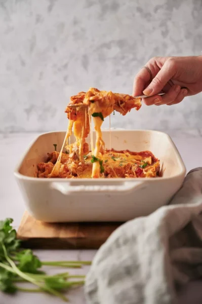 cooked enchiladas with cheese, meat and veggies in an oven dish