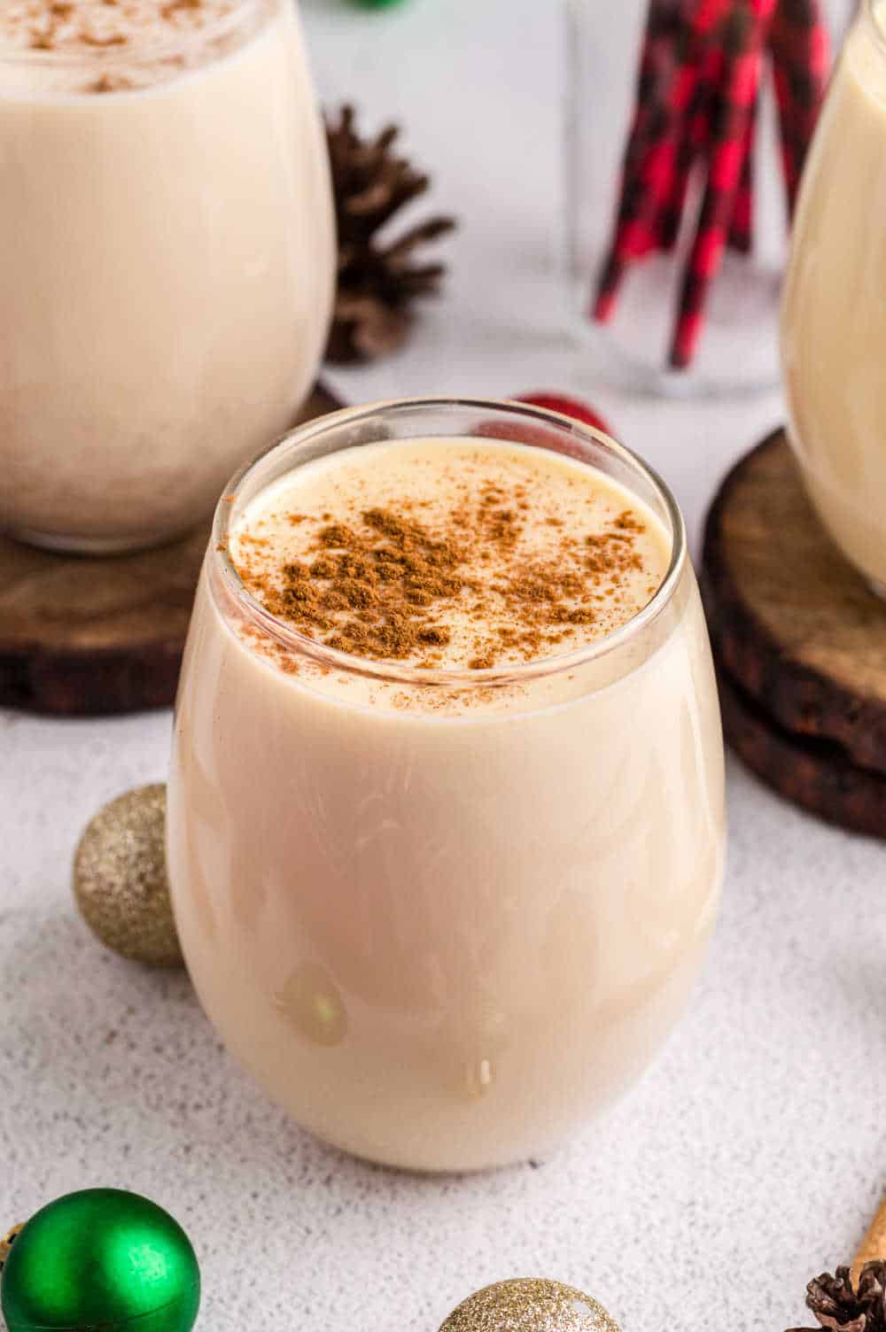 eggnog in small glass cup topped sprinkled with cinnamon, with festive decoration 