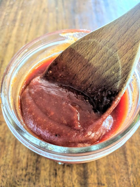 Easy honey BBQ sauce in mason jar with wooden spoon.