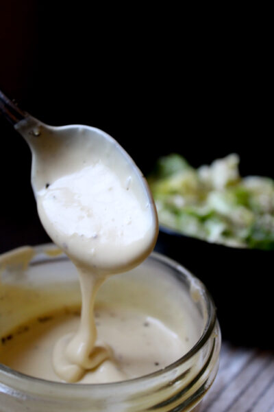 caesar dressing on spoon in jar