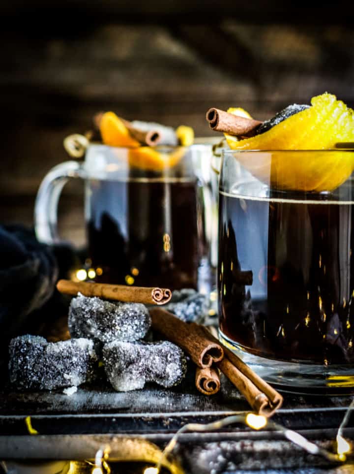 warm sugar plum coocktail on 2 beer glasses wth cinnamon barks and plums