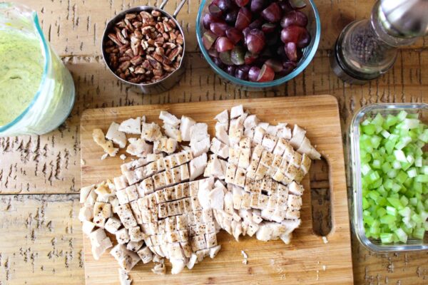 baked chicken breast, finely chopped celery, chopped grapes, roasted pecans, and tarragon mayo sauce with cutting board.