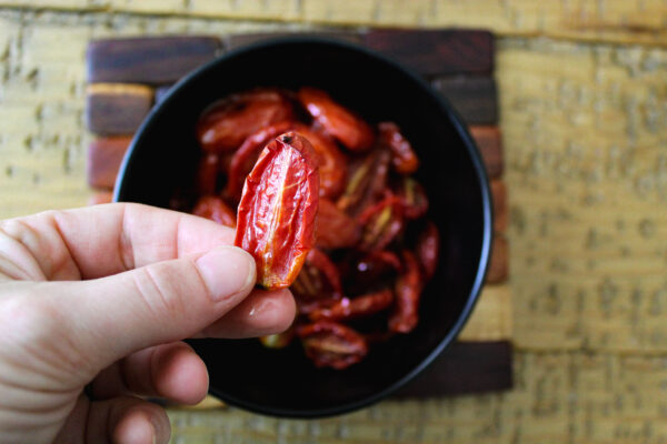 one semi dried tomato above bowl full of more