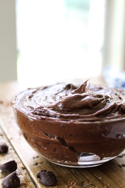 avocado chocolate pudding in clear bowl on counter with chocolate chips around