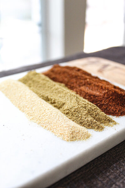 homemade taco seasoning ingredients - garlic powder, cumin, and chili powder on cutting board