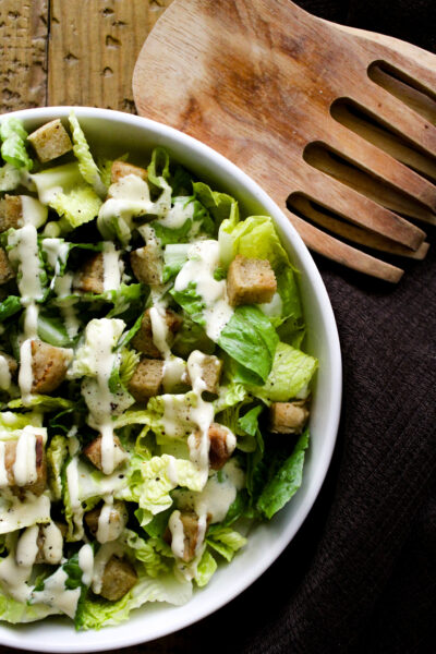 caesar dressing on salad in white bowl