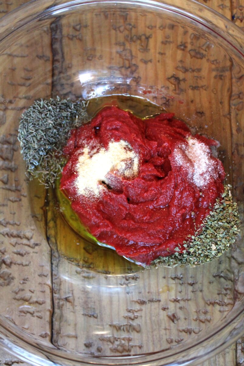 tomato paste, herbs, salt, oil, and vinegar in mixing bowl 