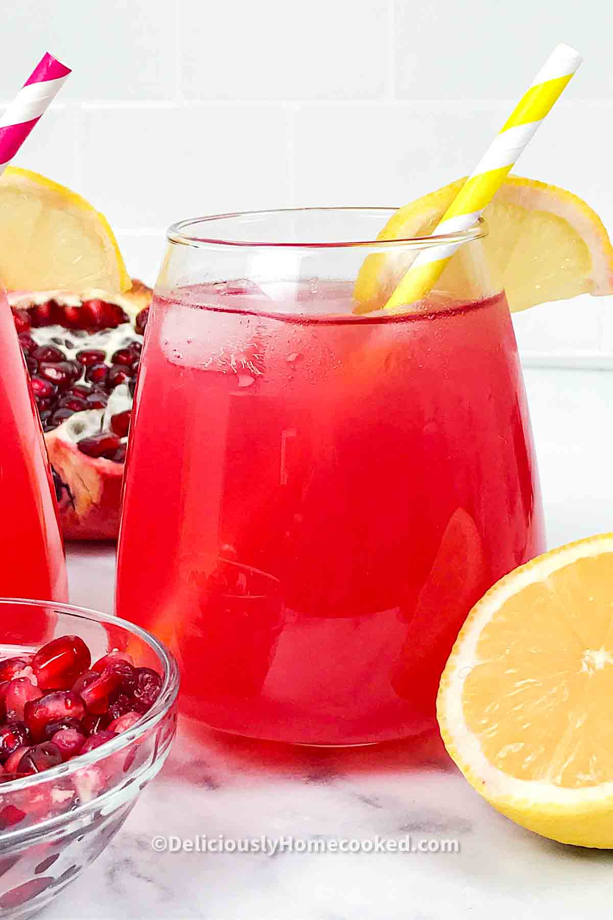 pomegranate lemonade with lemon slice and yellow white straw in a glass