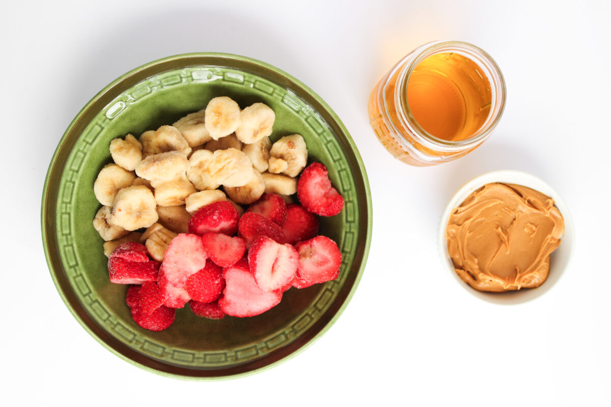 Ingredients for PB&J Smoothie on a white background in individual bowls.