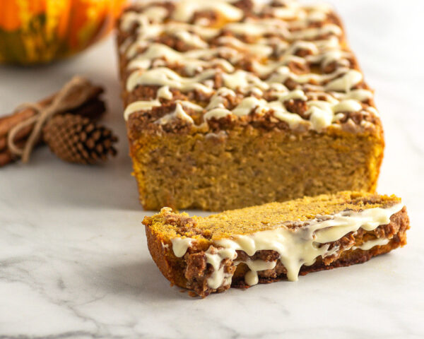 baked gluten-free pumpkin bread loaf with a streusel crumble topping and a drizzle of icing