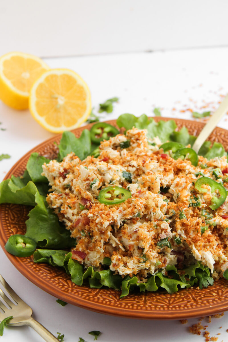 Chicken salad on a bed of lettuce on an orange plate.