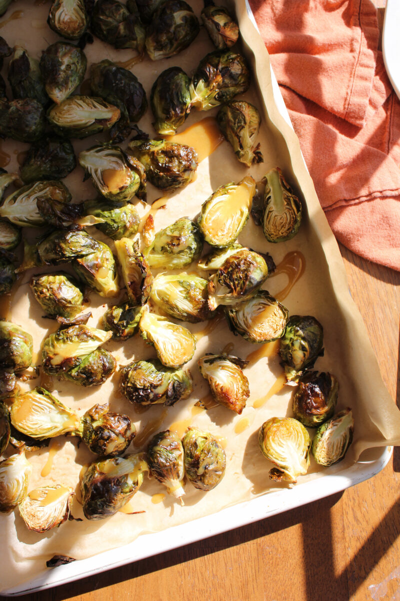 Corner of sheet pan with brussels sprouts on wood surface.