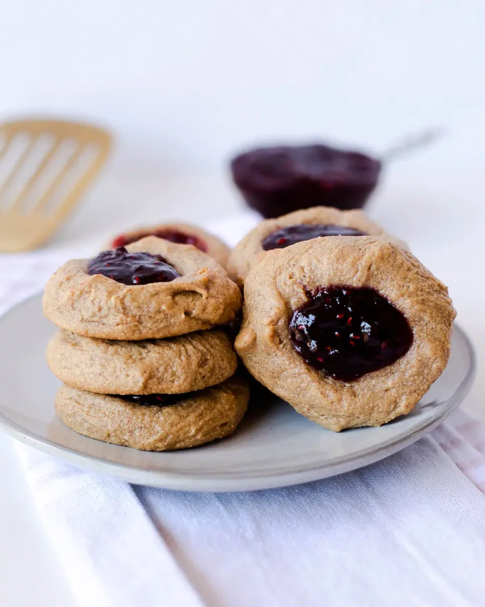 peanut butter and jelly thumbprint cookies on a white plate