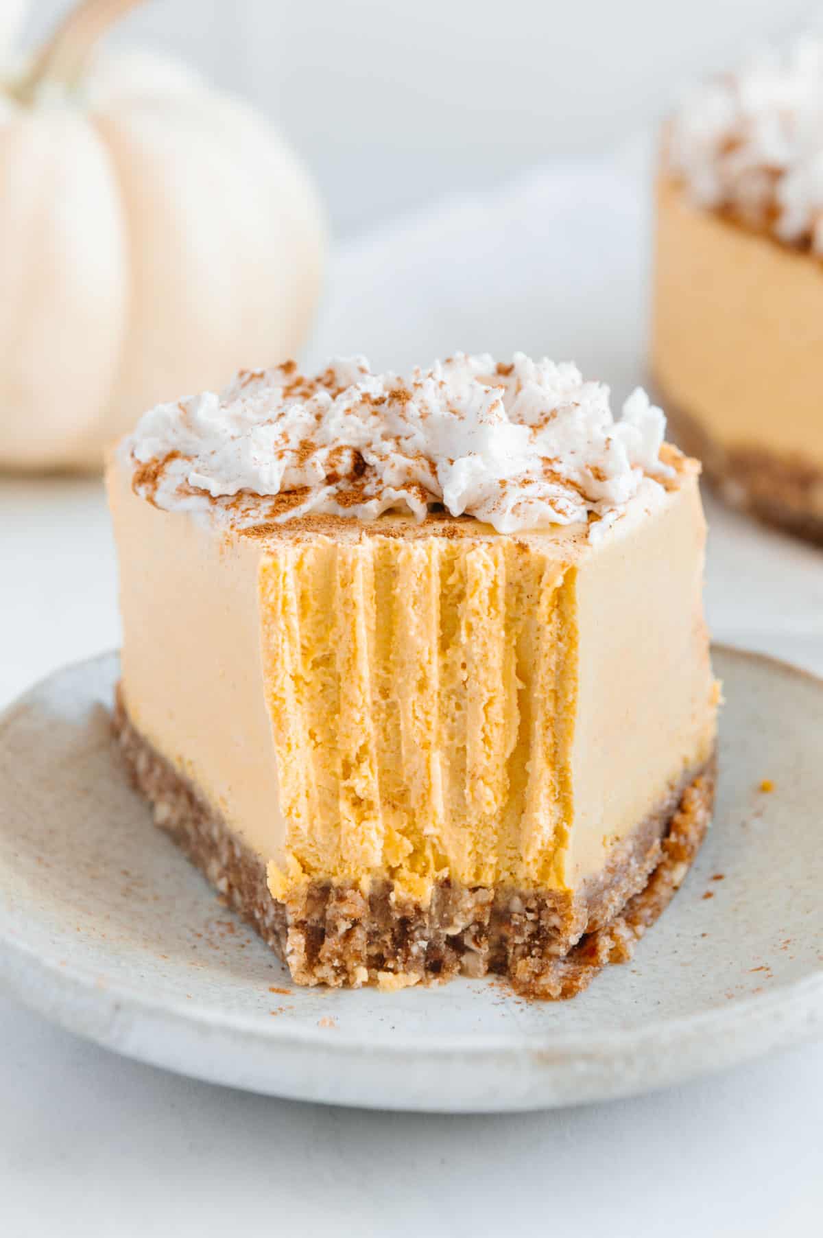 a slice of creamy pumpkin pie topped with cream and cinnamon