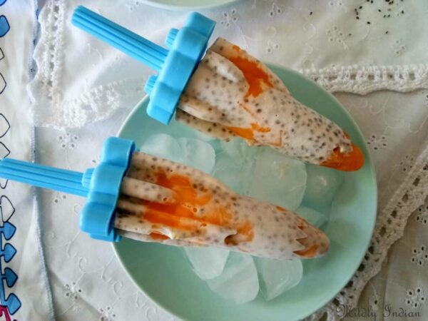 Pumpkin chia dairy free popsicles serve over ice cubes on a light blue platelet