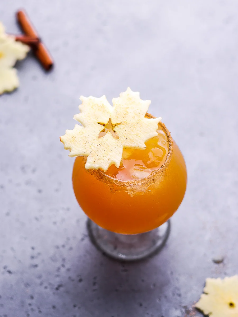 apple cider cocktail rimmed with sugar and cinnamon powder with garnished with apple slices