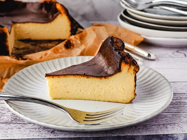 a slice of San Sebastian Cheesecake or basque burnt cheesecake on a white saucer plate with a fork