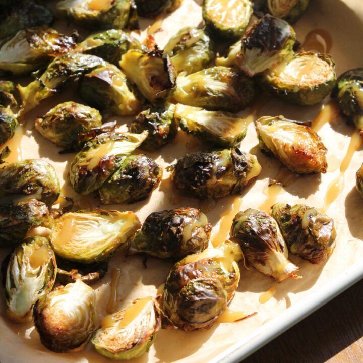 Roasted brussels sprout on a sheet pan with wood table behind.