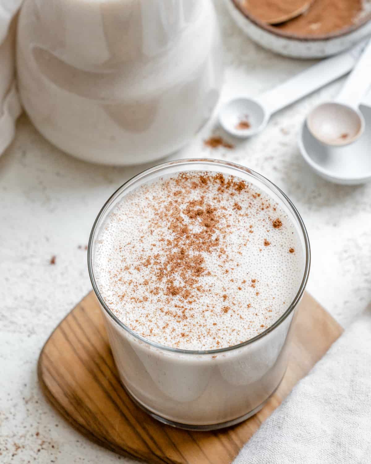 Vegan eggnog sprinkled with cinnamon in a glass on a wooden board