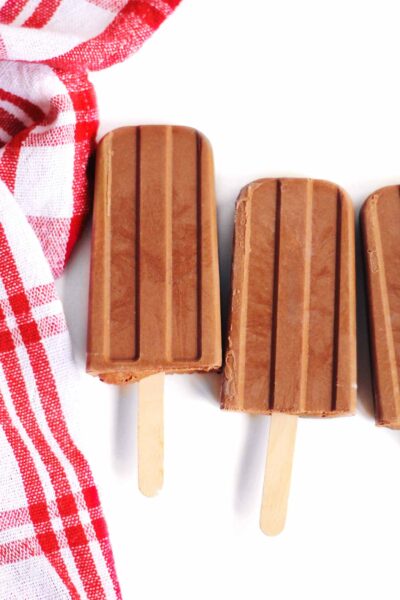 3 pcs of vegan fudgesicle laid on a hite surface with a red and white  cloth  on the side