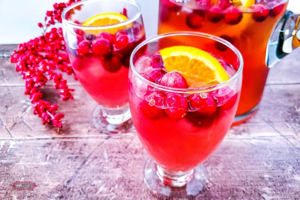 Christmas vodka punch with cranberries and lemon wedge in cocktail glasses, Christmas decor on the background