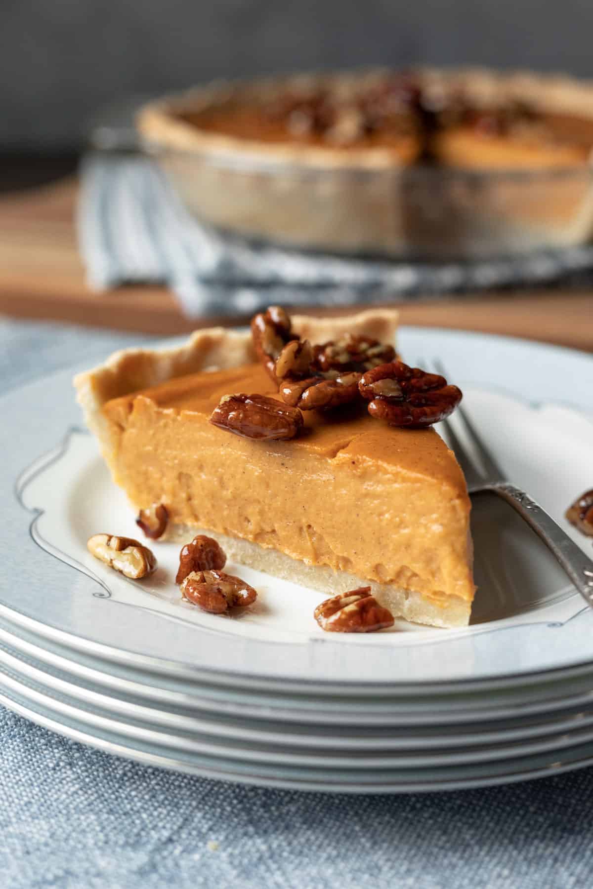 a slice of sweet potato pie  topped with walnuts on a plate with fork
