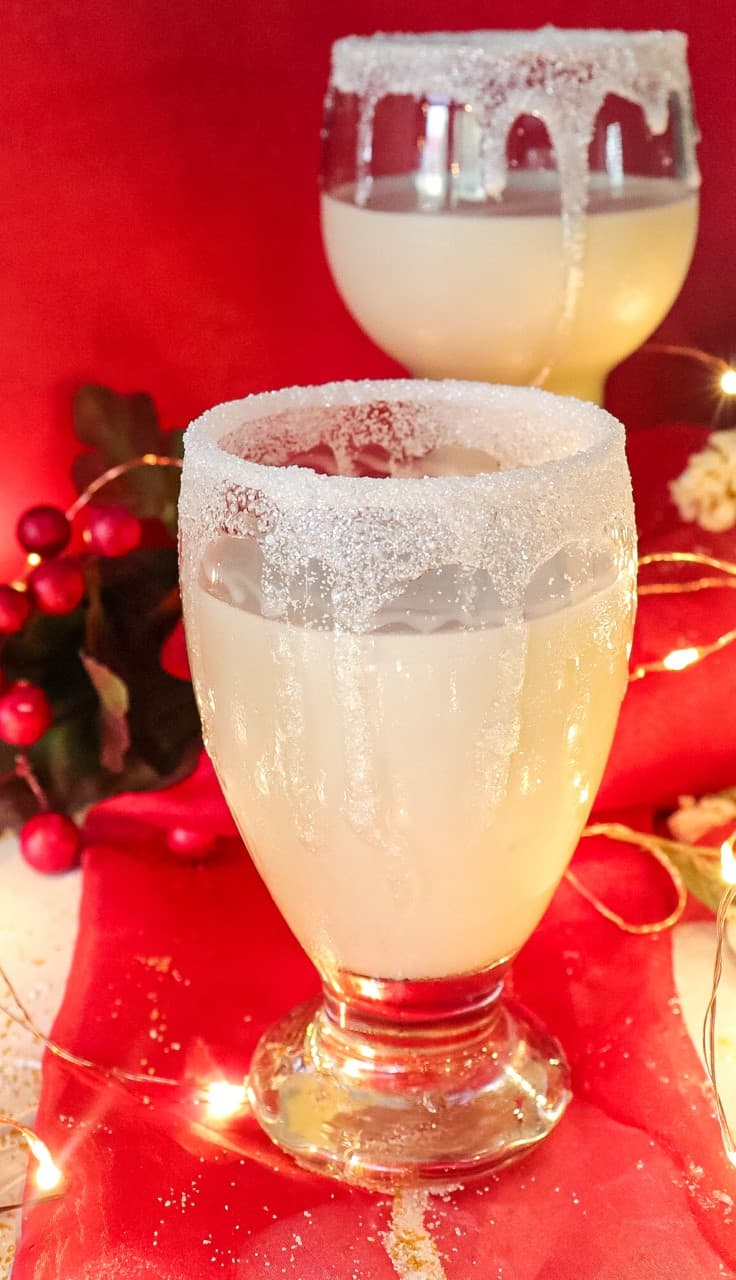 white martini rimmed with sugar crystals, Christmas decor and lights on the background