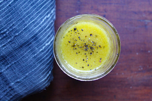 homemade apple cider vinaigrette on a glass jar atop a table with blue cloth on the side