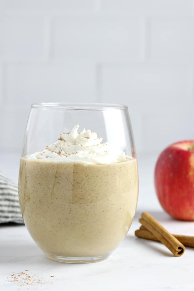 apple pie smoothie with whipped cream sprinkled with cinnamon powder in a glass