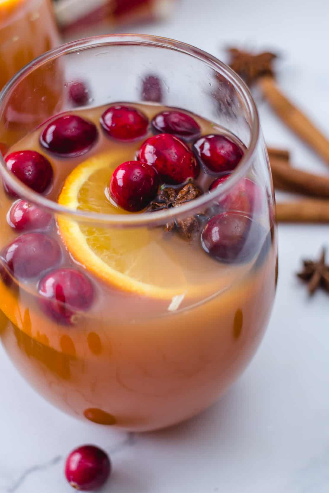 apple cider punch with cranberries, orange slices and star anise in a glass